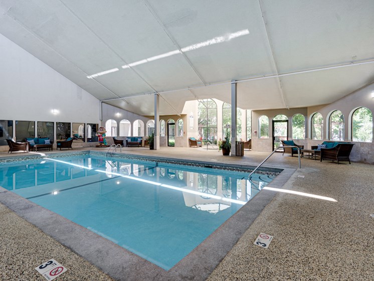 Indoor pool with high ceiling and patio seating